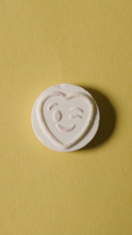 Vertical-Video-Close-Up-Of-Vertical-Video-Of-Hand-Holding-Heart-Candy-With-All-Yours-Message-On-Yellow-Background